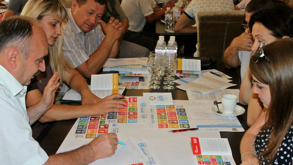 Group of people sitting around a desk looking at SDG brochures